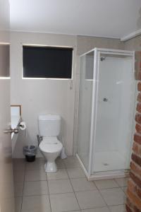 a bathroom with a toilet and a shower stall at Sarina Beach Motel in Sarina