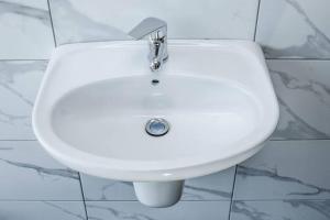 a white sink in a white tiled bathroom at Airb&b Homestay in Boma la Ngombe