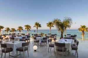 ein Restaurant am Strand mit Tischen und Stühlen in der Unterkunft Constantinos the Great Beach Hotel in Protaras