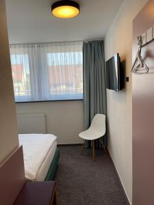 um quarto de hotel com uma cama e uma cadeira e uma televisão em Ulmer Münster Hotel em Ulm