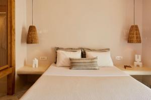 a bedroom with a bed with white sheets and pillows at Hermes Hotel in Kamari