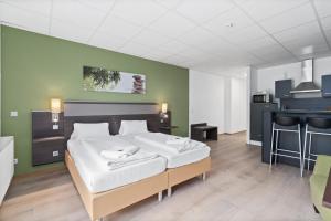 フリードリヒスハーフェンにあるFerien & Business Apartments Hotel Adlerの緑の壁、ベッド付きのベッドルーム1室