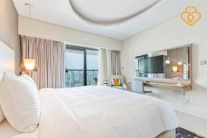 a white bedroom with a large bed and a desk at Keyplease New 1 BR Apt in Paramount Towers by Damac 4803 in Dubai
