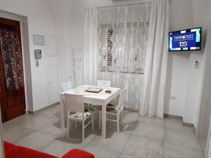 un tavolo bianco con sedie in una camera con TV di LA CASA DEI DESIDERI a Oria