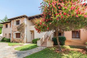 a house with a tree in front of it at Residenze Coda Cavallo - Punta Aldia - Casa delle Sughere in Puntaldia