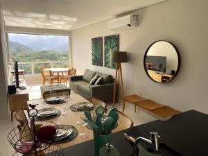 a living room with a couch and a mirror at Apartamento 3 suítes Camburi in Camburi