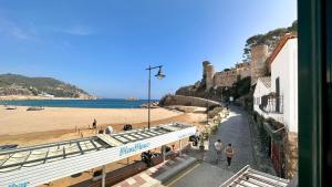 - une vue sur une plage avec un château et des personnes marchant dans l'établissement Lets Holidays apartment Can Telm, à Tossa de Mar
