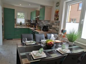 ハッセルフェルデにあるPremium-Plus-Ferienhaus Skadi Iのキッチン(緑のキャビネット、ワイングラス付きのテーブル付)
