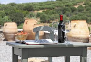 a table with a bottle of wine and two glasses at Amvikas suites-Sitia in Sitia