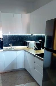 La cuisine est équipée de placards blancs, d'un évier et d'un four micro-ondes. dans l'établissement Apartaments Victoria, à Poreč