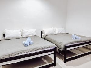Belukar Lodges Private Homestay في بانتايْ سينانج: سريرين يجلسون بجانب بعض في غرفة