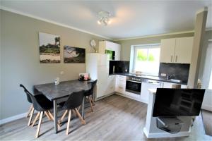 a kitchen with a table and chairs and a television at Rosen-Haus in Fehmarn +14 photos