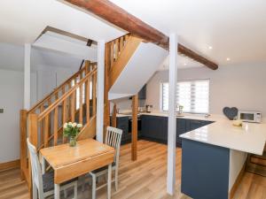 cocina y comedor con armarios azules y mesa en Thimble Cottage en Blandford Forum