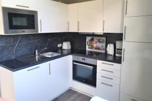 Una cocina con gabinetes blancos, un fregadero y un microondas. en Untere Teichwohnung, en Fehmarn