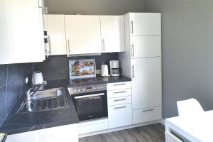Una cocina con electrodomésticos y gabinetes blancos. en Untere Teichwohnung, en Fehmarn