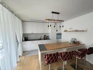 cocina con armarios blancos y mesa de madera en Wohnung auf dem Bürgenstock, en Kehrsiten