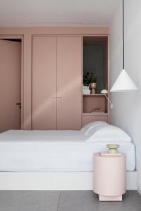 Un dormitorio con una gran cama blanca y una lámpara en Neo Suites, en Fira