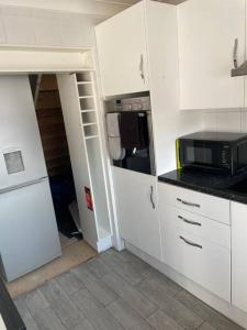 La cuisine est équipée de placards blancs et d'un four micro-ondes. dans l'établissement 3 Bed Sleep 6, Bootle/Aintree, à Bootle