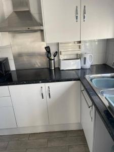 a kitchen with white cabinets and a sink at 3 Bed Sleep 6, Bootle/Aintree in Bootle