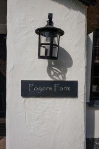 a sign on the side of a white building with a light at Poyers Farmhouse in Wrafton