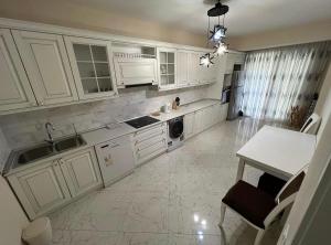 cocina con armarios blancos, fregadero y mesa en Park Azure great apartment by Baku housing, en Baku
