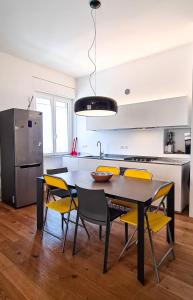 a kitchen with a dining table and yellow chairs at Dorico Apartment in Ancona