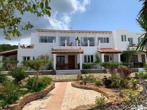 a white house with a garden in front of it at Apartamentos Vista Vedrá in La Savina