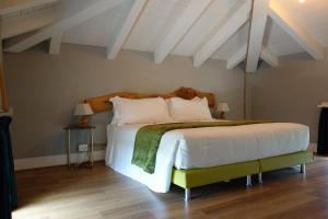 1 dormitorio con 1 cama grande con sábanas y almohadas blancas en Capriccio Art Hotel, en Serravalle Scrivia