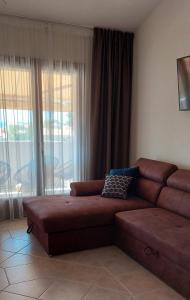 un soggiorno con divano marrone di fronte a una finestra di Apartaments Victoria a Poreč (Parenzo)
