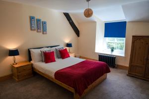 a bedroom with a bed with red pillows and a window at Poyers Farmhouse in Wrafton