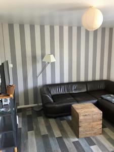 Un sofá de cuero negro en una sala de estar con paredes rayadas. en Family, en La Réorthe 5 fotos más