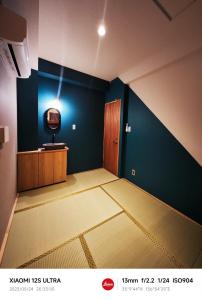 an empty room with a tv on a blue wall at 2023年6月開業 サカエ ゲストハウス in Nagoya