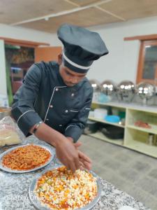 Un uomo con un cappello da chef che prepara due pizze di The Royal Maryul Banquet Hall , Restaurant & Resort - Leh a Stak