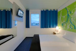 a room with a bed and a tv and blue curtains at B&B Hotel Paderborn in Paderborn