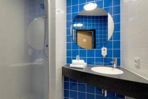 a blue tiled bathroom with a sink and a mirror at B&B Hotel Paderborn in Paderborn