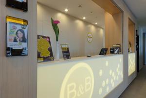 a reception counter in a store with a flower on the wall at B&B Hotel Paderborn in Paderborn