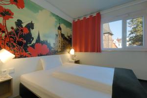 ein Schlafzimmer mit einem weißen Bett und einem Gemälde an der Wand in der Unterkunft B&B Hotel Oldenburg in Oldenburg