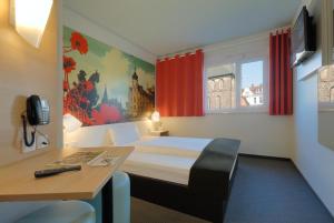 a hotel room with a bed and a desk and a window at B&B Hotel Oldenburg in Oldenburg