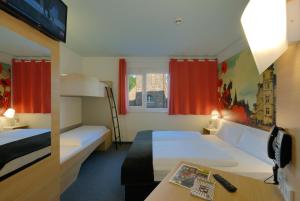 a hotel room with two beds and a desk at B&B Hotel Oldenburg in Oldenburg