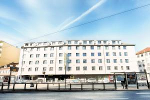 ein großes weißes Gebäude in einer Stadtstraße in der Unterkunft B&B Hotel Nürnberg-Plärrer in Nürnberg