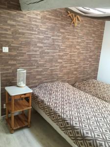 1 dormitorio con 1 cama y mesita de noche junto a una pared de ladrillo en Family, en La Réorthe