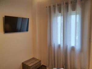 een televisie aan een muur naast een raam bij Island View Apartments in Moúdhros