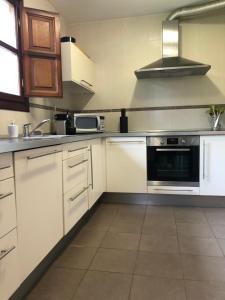 cocina con armarios blancos y fogones en Casa Mojapies, en Ribadesella