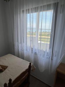 a bedroom with a large window with white curtains at Apartments Linic in Nin