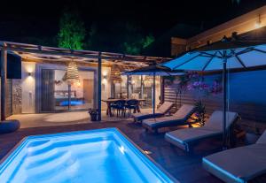 a swimming pool with chairs and umbrellas in a backyard at The Cave Villa in Matala