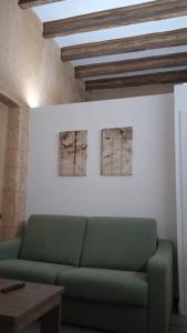 a living room with a green couch and two paintings at Apartamento Barrio Alto in Sanlúcar de Barrameda