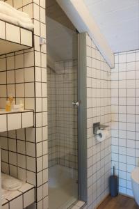 um chuveiro na casa de banho com azulejos brancos em Capriccio Art Hotel em Serravalle Scrivia