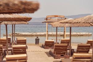 Mandraki Beach Resort في Mandraki: مجموعة من الكراسي والمظلات على الشاطئ