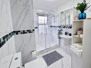 a white bathroom with a shower and a sink at Spacious room with sofa in London