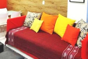 um sofá vermelho com almofadas coloridas em Flat Felipe de Oliveira no Rio de Janeiro